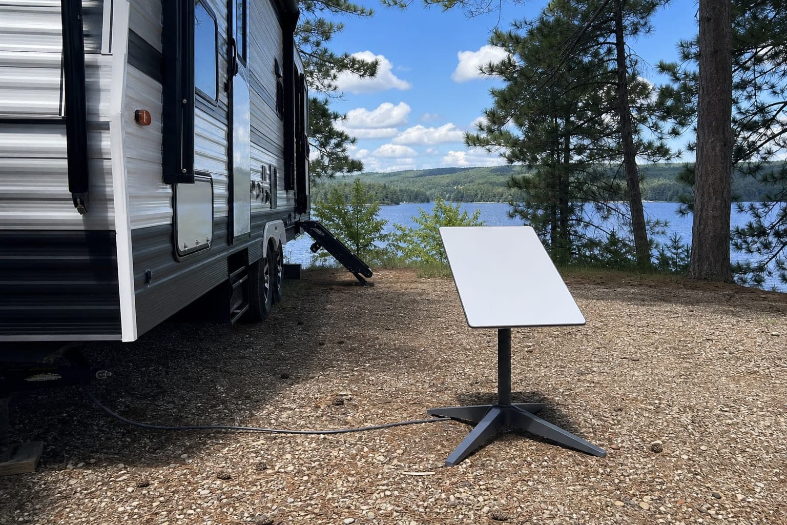 Starlink Gen2 dish beside a camping trailer at a lakeside site
