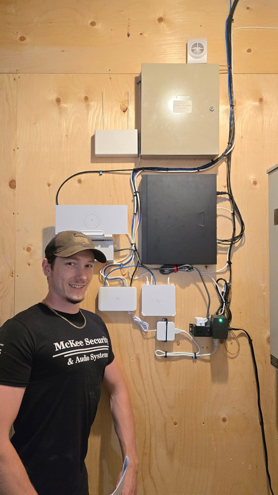 McKee technician standing beside a wall-mounted security and equipment board