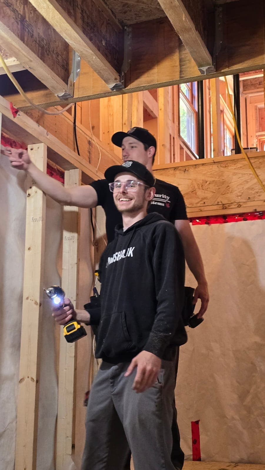 Two McKee technicians running low-voltage wiring during a construction rough-in